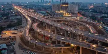 Modern highway interchange and city skyline at dusk, symbolizing infrastructure development and job growth.