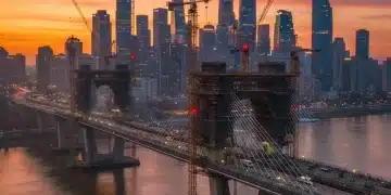 Modern bridge construction with city skyline at sunset, symbolizing infrastructure development.
